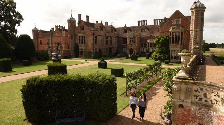 Two female visitors in the garden in front of the house at Charlecote Park, Warwickshire